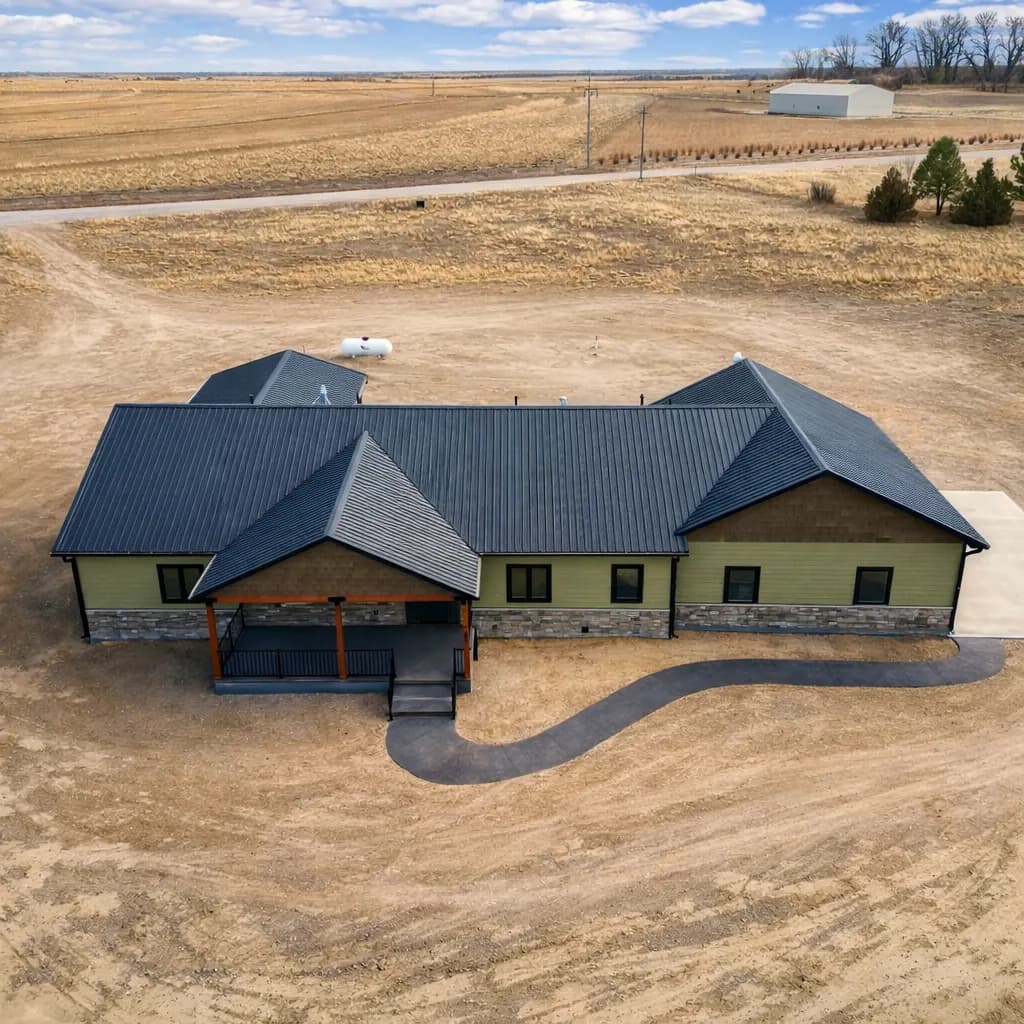 Aerial view of a finished post-frame barndominium shell with a dark steel roof