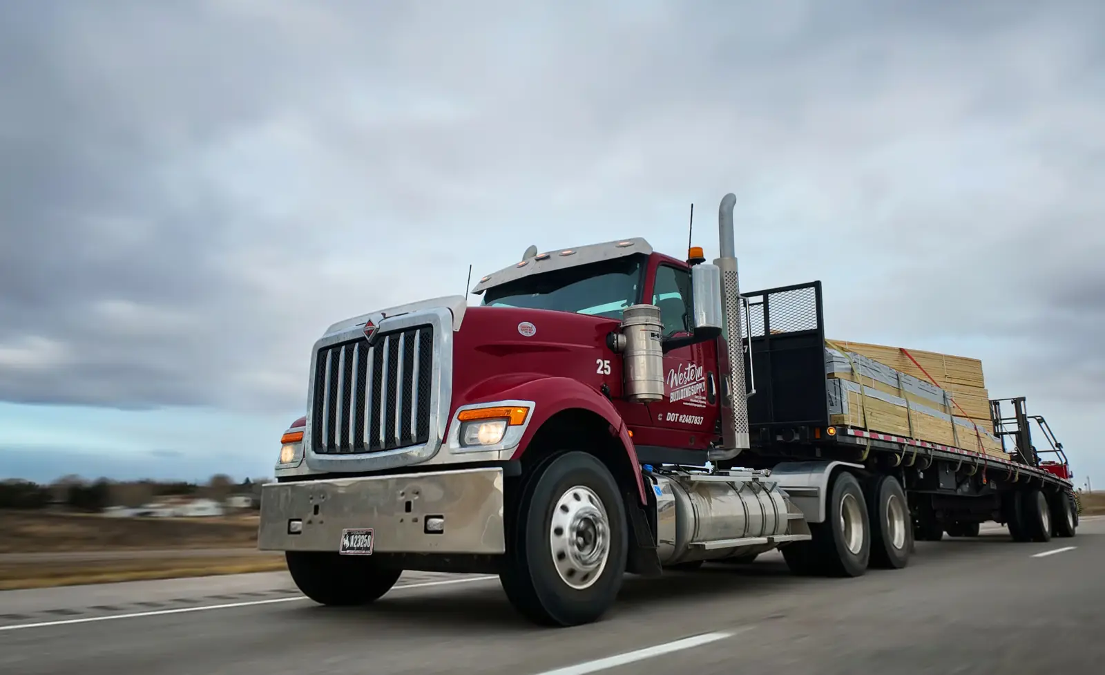 Western Building Supply truck hauling a post-frame building package down the highway
