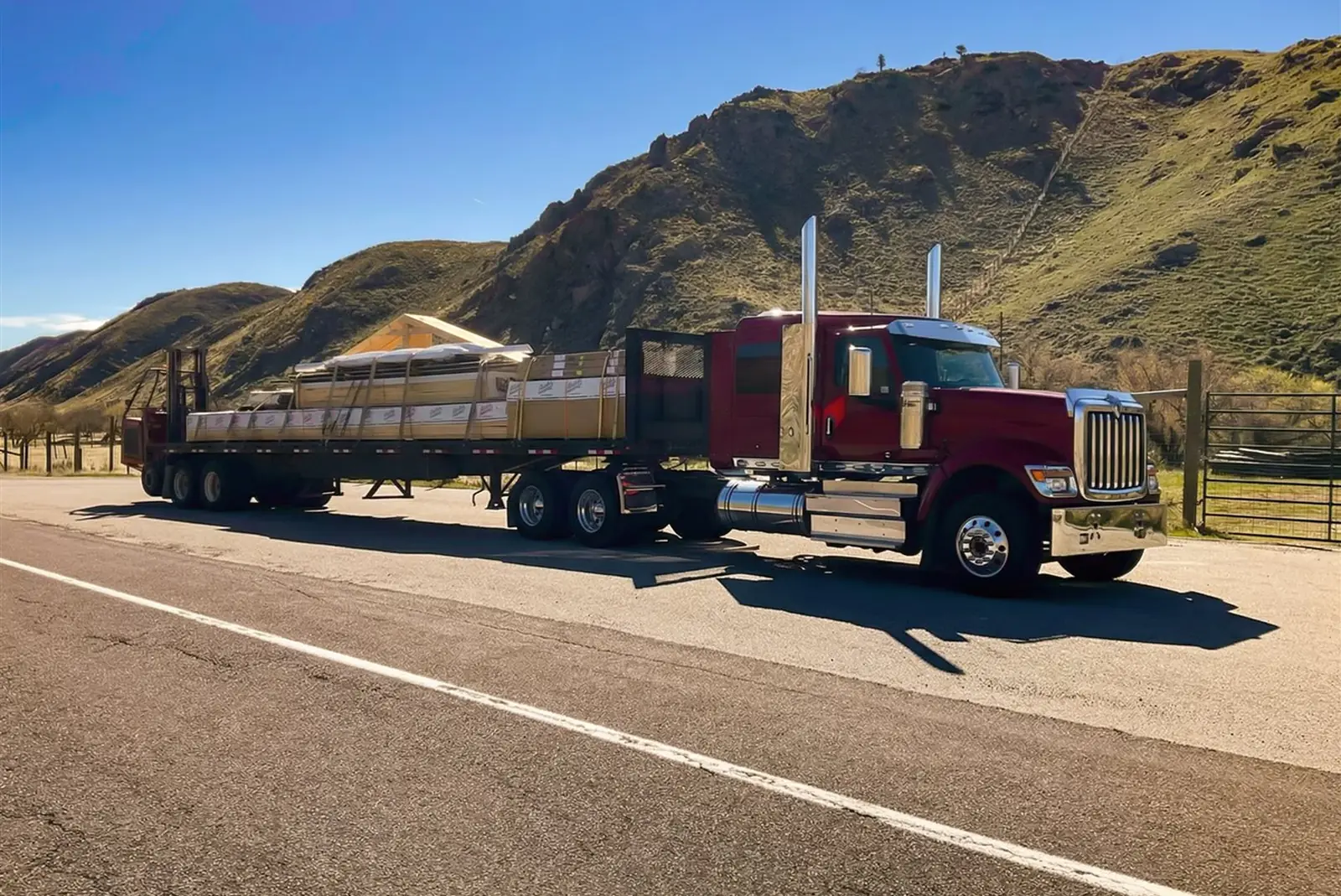 Western Building Supply flatbed loaded with a post-frame building package on a mountain highway