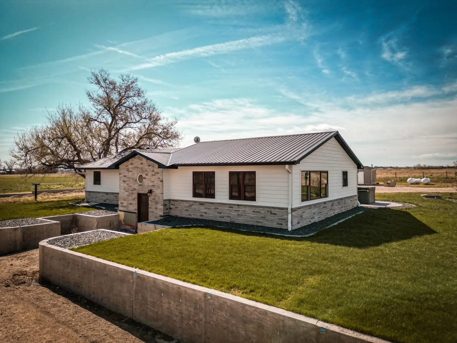 Single-story post-frame home with stone accents and a green lawn
