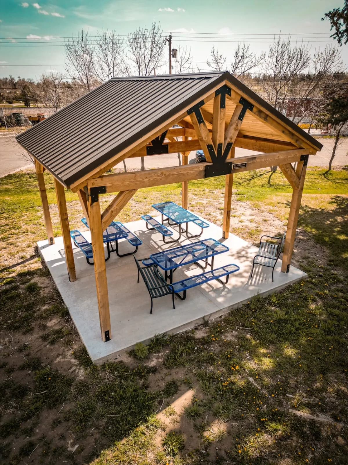 Timber-frame pavilion with a steel roof over a concrete patio