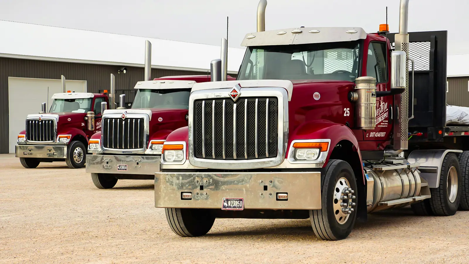 Row of red Western Building Supply delivery trucks